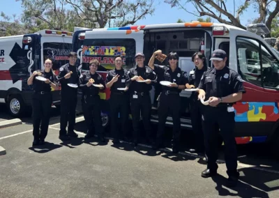 A group of Premier Ambulance EMS workers eating pizza next to their ambulance