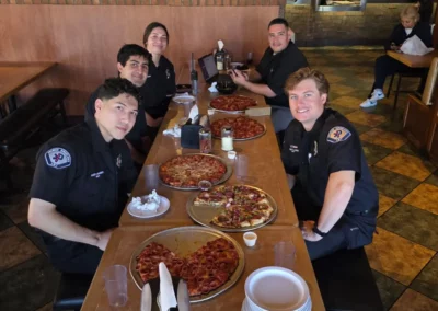 A group of EMS workers eating at a pizza restaurant.