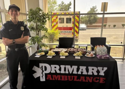 An EMS worker stands next to a Premier Ambulance table with burritos and snacks
