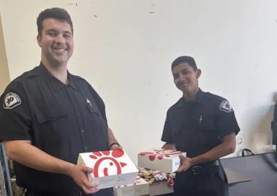 Two EMS workers smile, holding up Chik-fil-a boxes