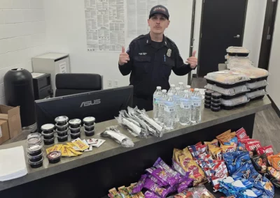 A premier ambulance EMS worker stands behind a counter with snacks and meals for other workers.