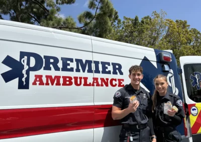 Two EMS workers stand next to their ambulance and enjoy burritos.