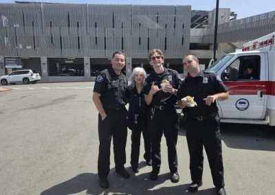 Four EMS workers stand in a group by an ambulance, enjoying burritos