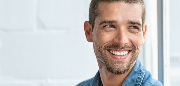 Man with a beard and brown hair smiling and looking off to the side