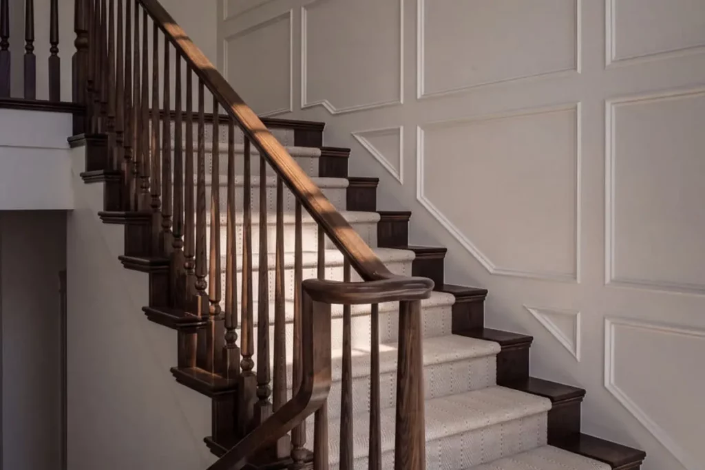 A wooden staircase with a white runner rug