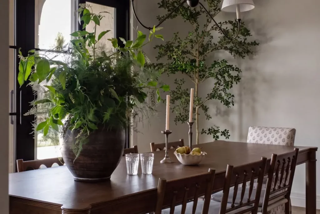 Wooden dining table with greens in a vase, pears in a bowl, and candles