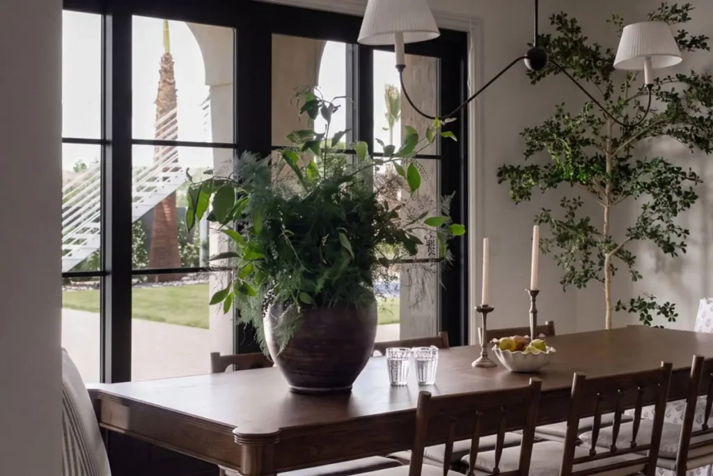 Wooden dining table with greens in a vase, pears in a bowl, and candles