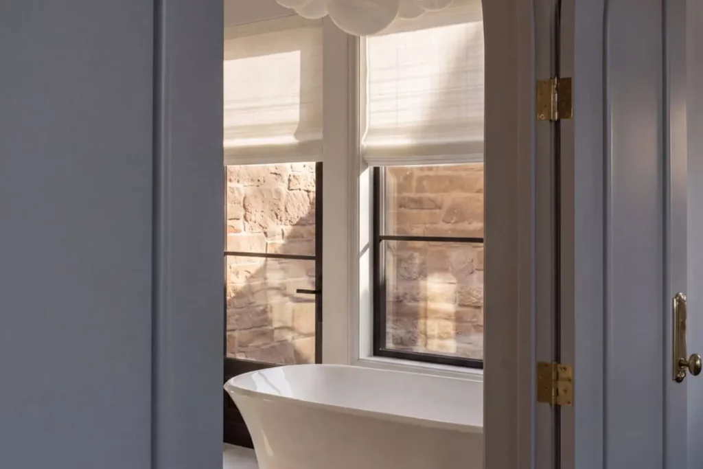 A white porcelain bathtub as seen through the bathroom door