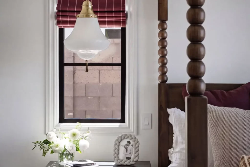 A nightstand and hanging lamp next to a canopy bed