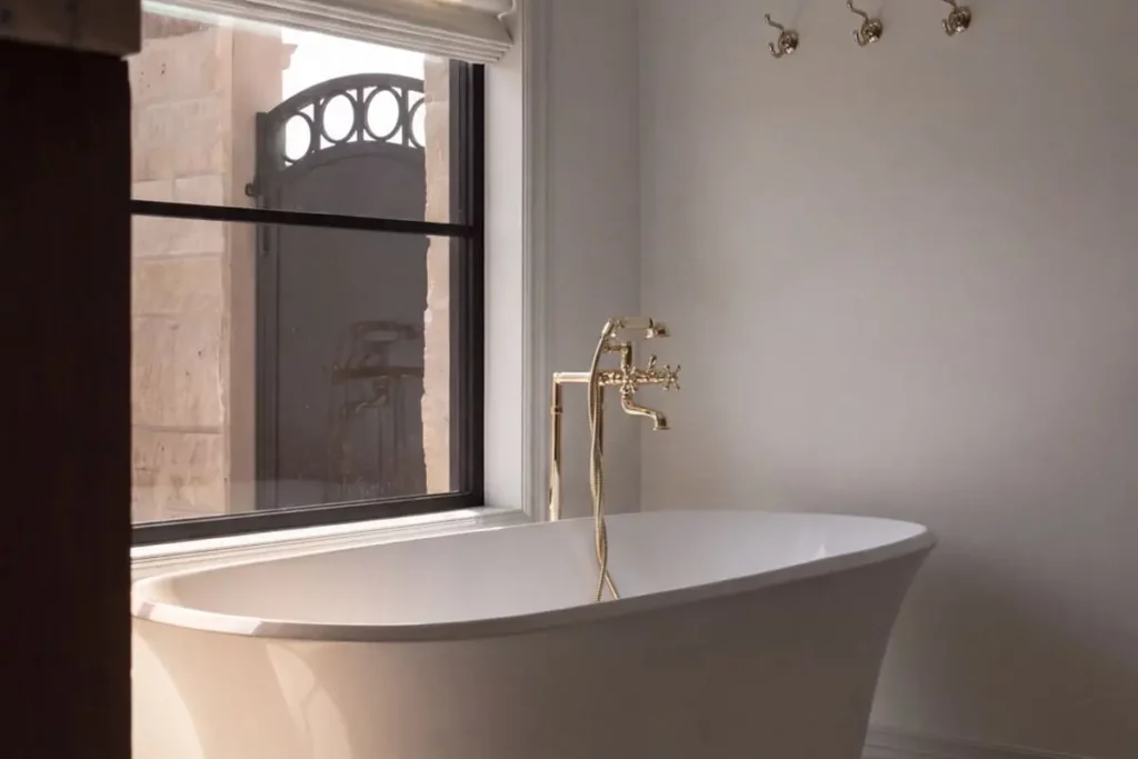 A white porcelain bathtub with a gold faucet