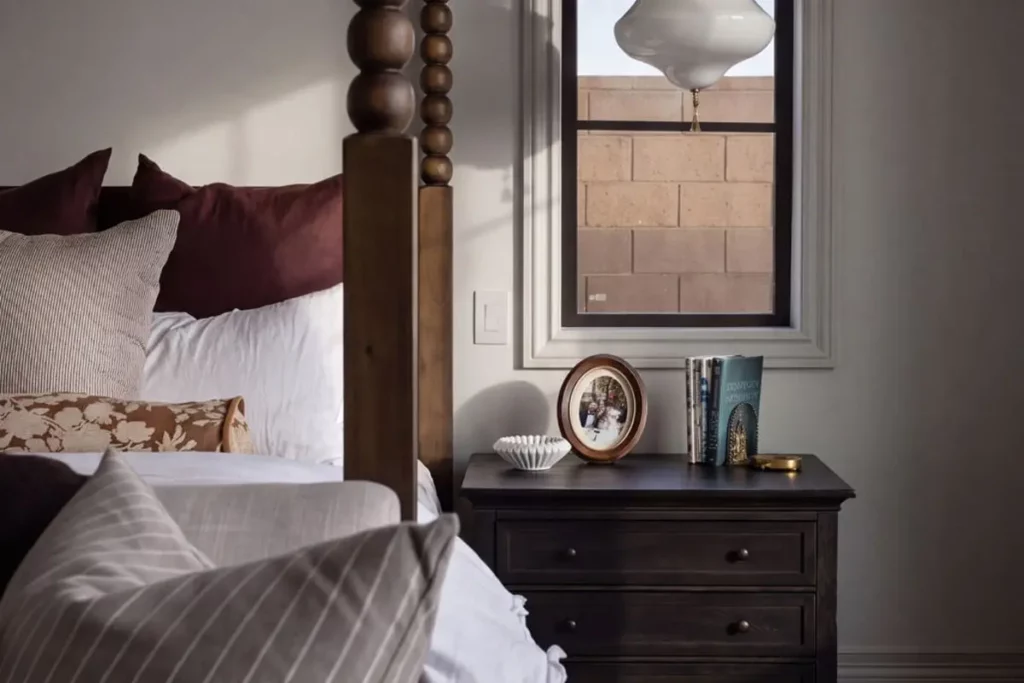 A nightstand and hanging lamp next to a canopy bed