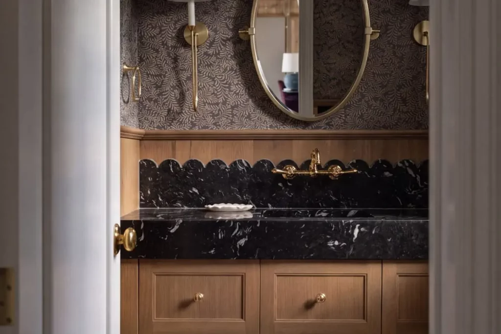 A black marble bathroom sink with a gold mirror