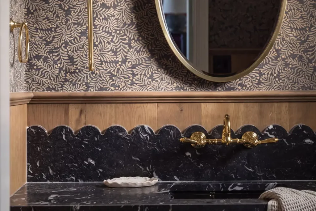 A black marble bathroom sink with a gold mirror