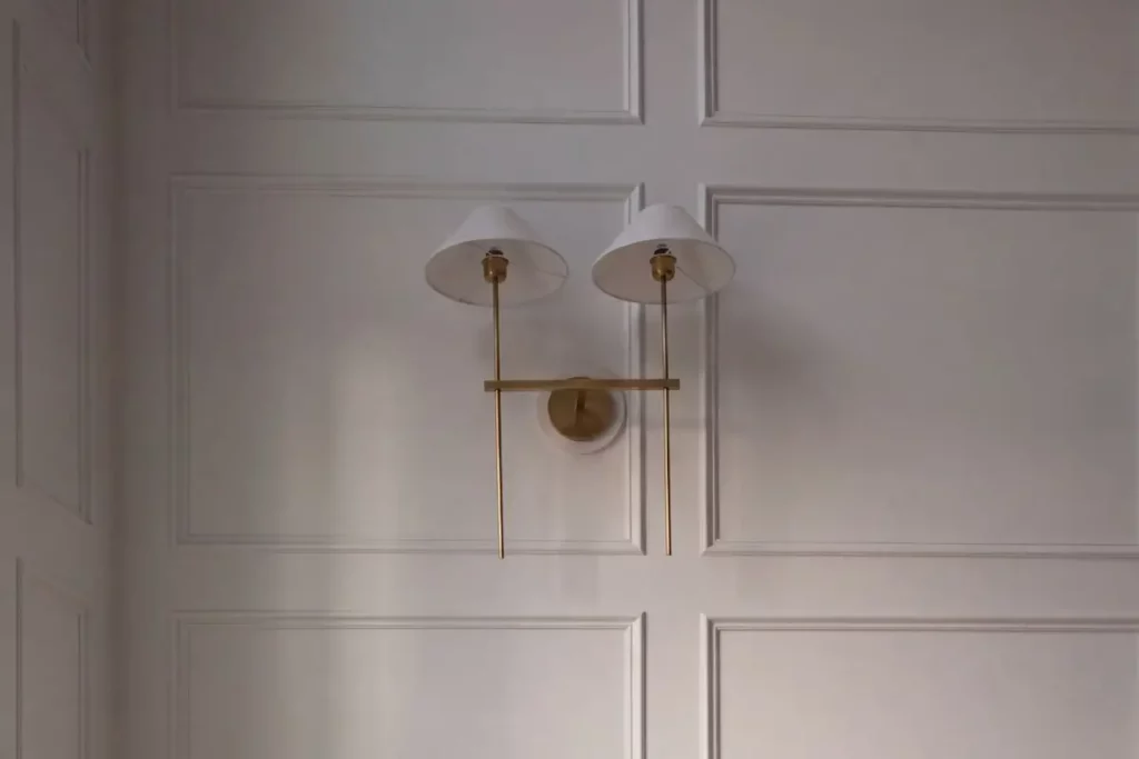 Gold sconces on white wood panelling