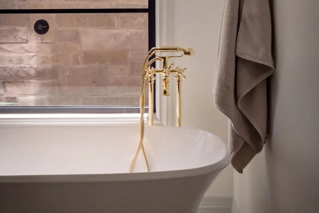 A white porcelain bathtub with a gold faucet