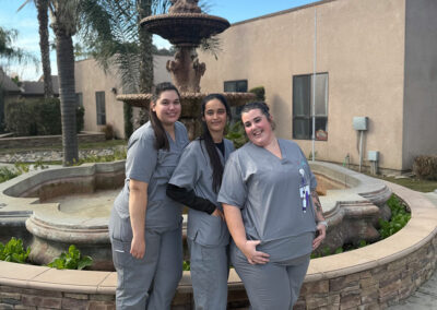 Three Prosperity graduates standing in front of a fountain